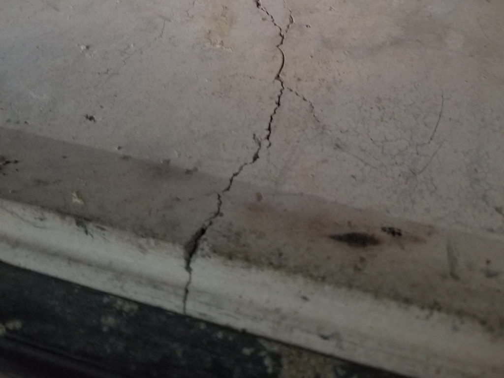 A crack in the floor of a bathroom, requiring chimney and dryer vent services.