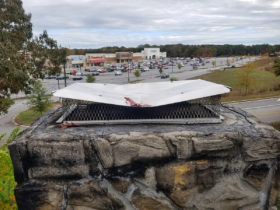 A grill with a chimney on top of a rock in a parking lot.