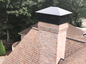 A chimney cap on top of a chimney providing chimney services.