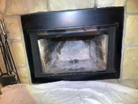 A fireplace with a black mantle is being cleaned during chimney services.