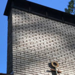 A brick chimney with a cross on top providing chimney services.