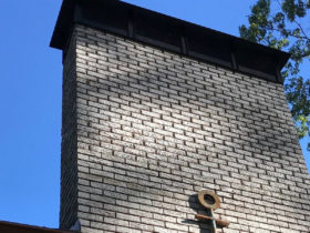 A brick chimney with a cross on top providing chimney services.