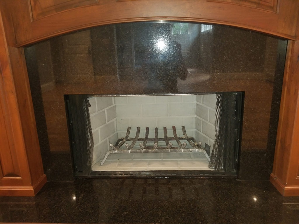 A fireplace with a black granite mantle for chimney services.