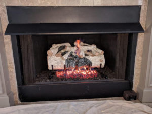 A fireplace with logs in it, requiring chimney services.